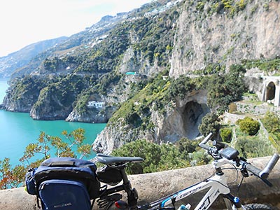Picture of a bike with the Conca dei Marini coast road in the background.